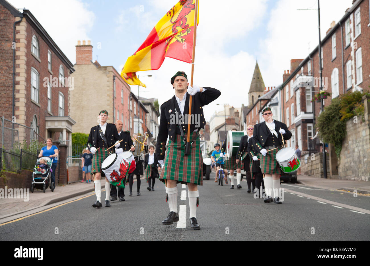 Cambria la banda a Welsh marching band con i percussionisti in Welsh kilts, Owain Gianfranco bandiera gallese e berretti marciando in Denbigh Foto Stock