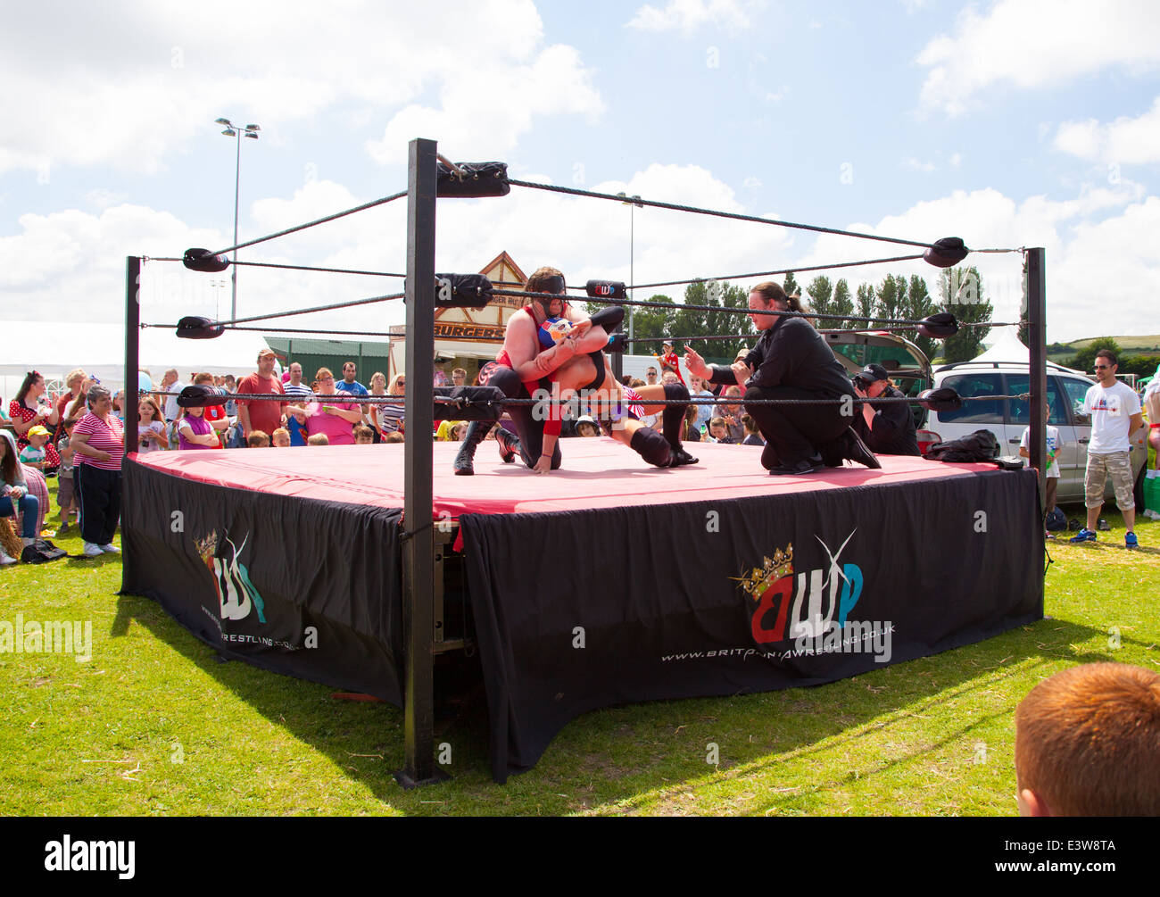 Un lottatore che indossa una maschera alle prese il suo avversario in un headlock / full nelson, sorvegliato da una folla in Denbigh storico carnevale estivo Foto Stock