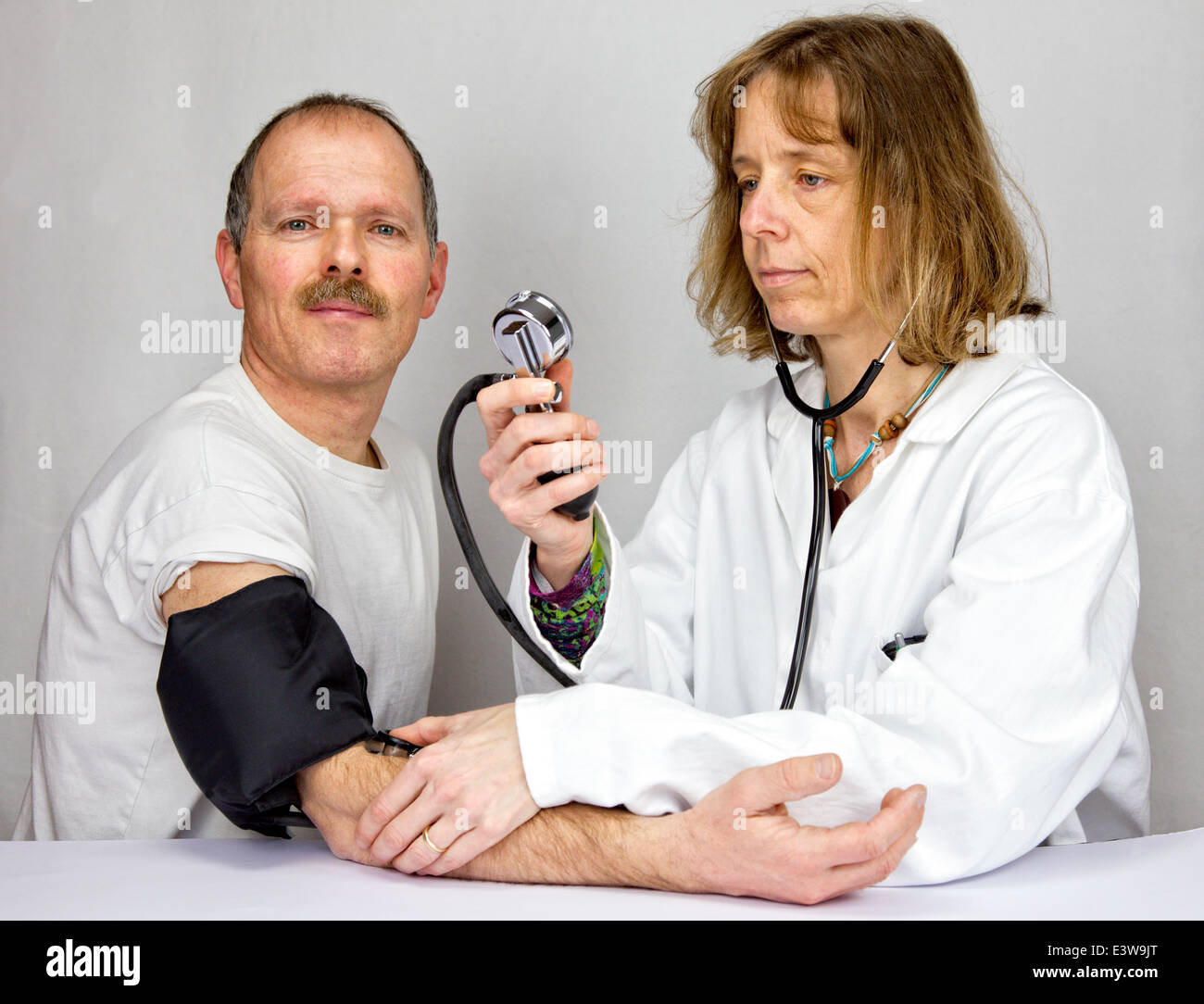 Medico controlla la pressione sanguigna di un paziente Foto Stock