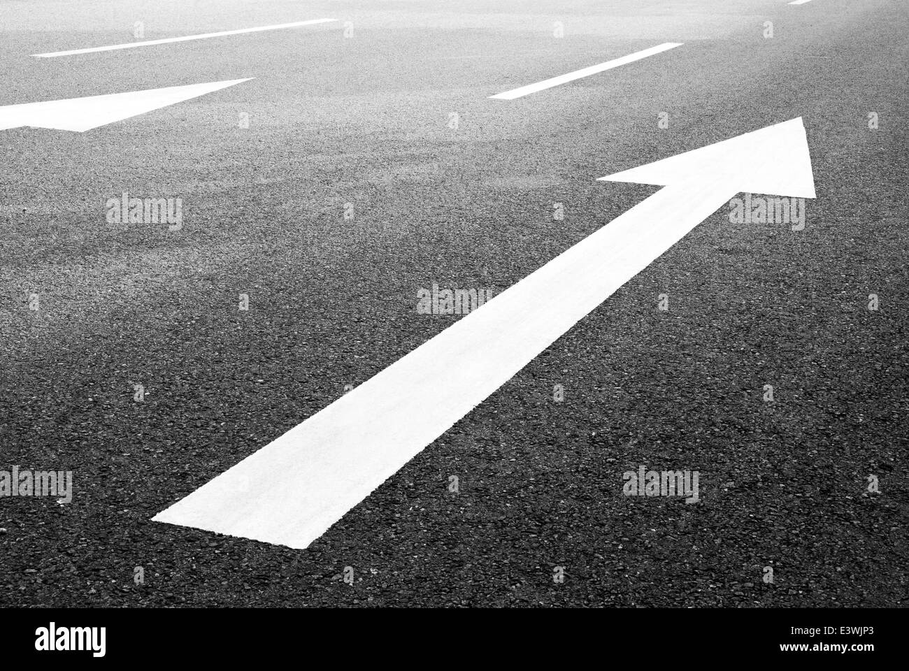 Bianco freccia direzionale su asfalto Foto Stock