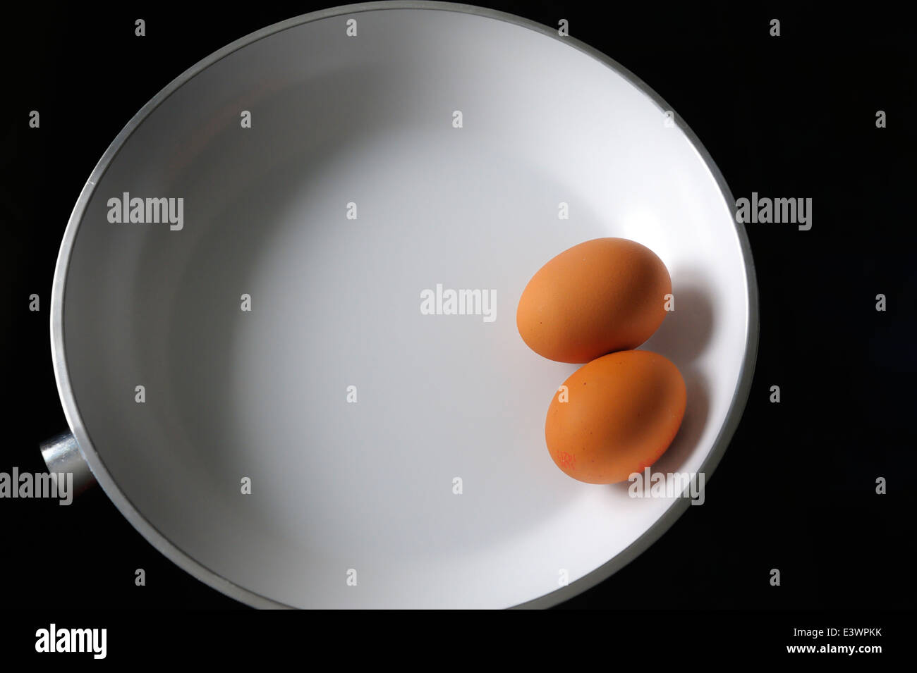 Due uova crude in un bianco padella Foto Stock