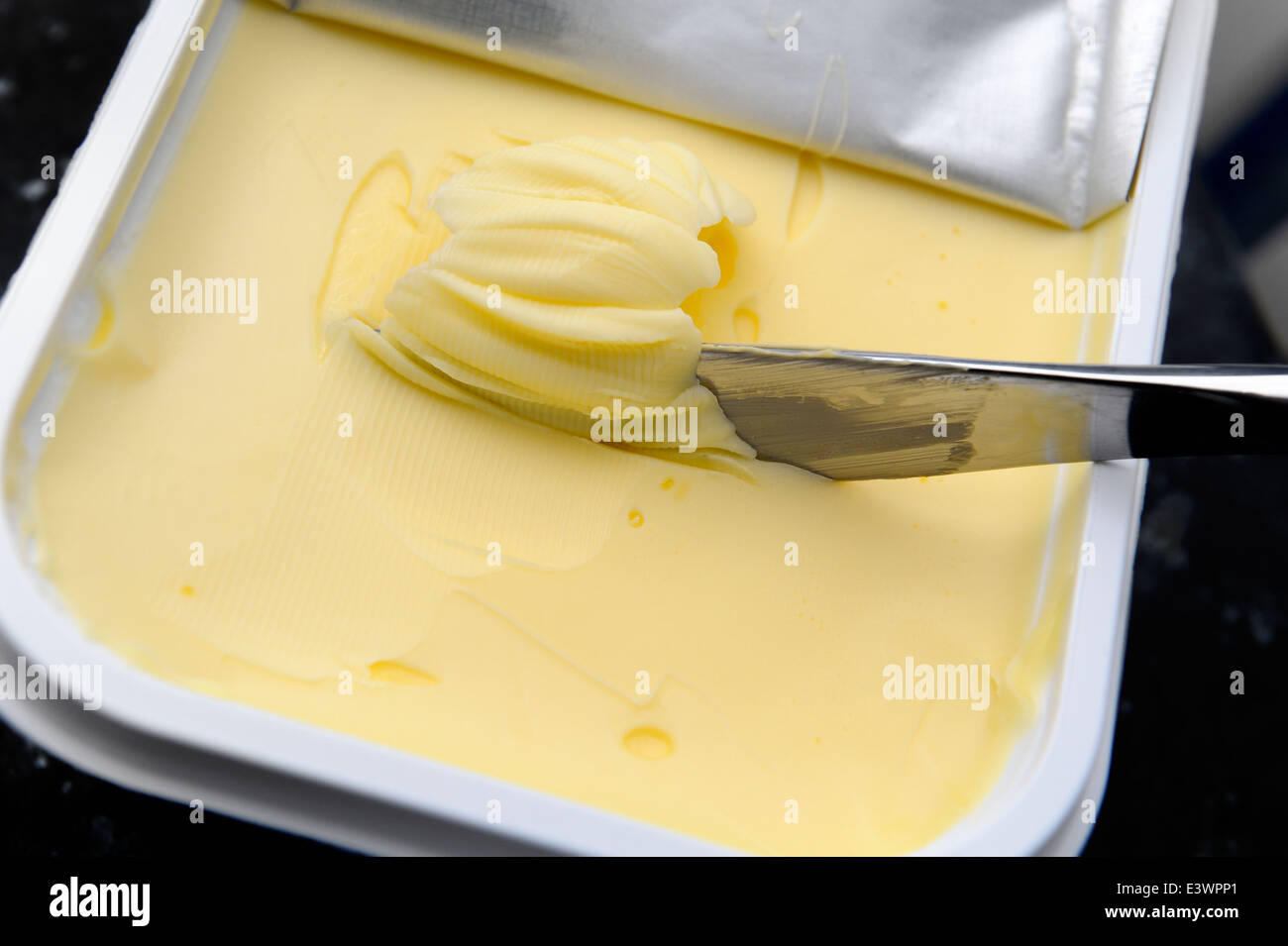 Il burro di essere raccolti su di un coltello per spalmata sul pane tostato Foto Stock