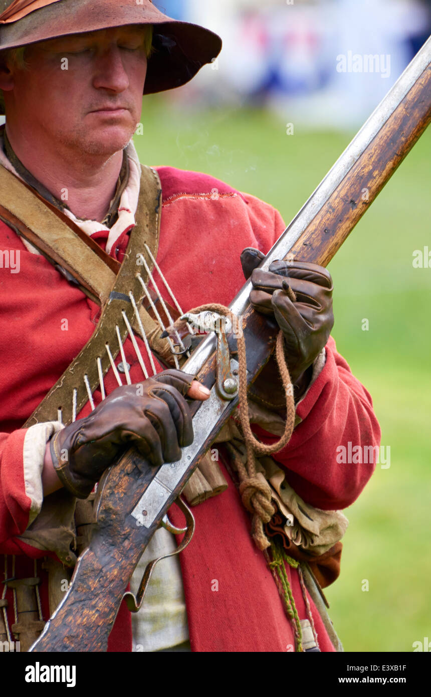 Attore nella guerra civile inglese Royalist musketeer uniforme tenendo un matchlock moschetto del periodo. Foto Stock