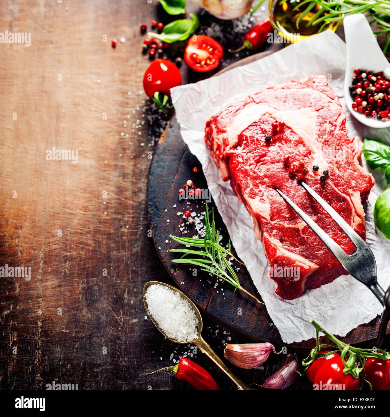Materie bistecca con forcella di carne e gli ingredienti su sfondo di legno Foto Stock