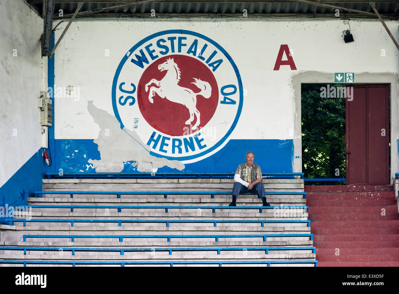 Un singolo spettatore si siede sui cavalletti abbandonati della ex rinomato club di calcio Westfalia Herne. Foto Stock