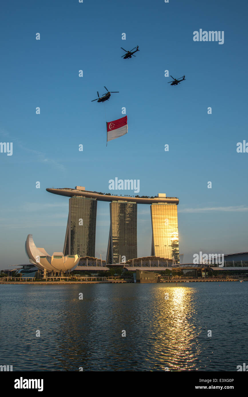 Elicotteri volare la bandiera di Singapore al tramonto sulla baia di Marina durante le prove della celebrazione della festa nazionale Foto Stock