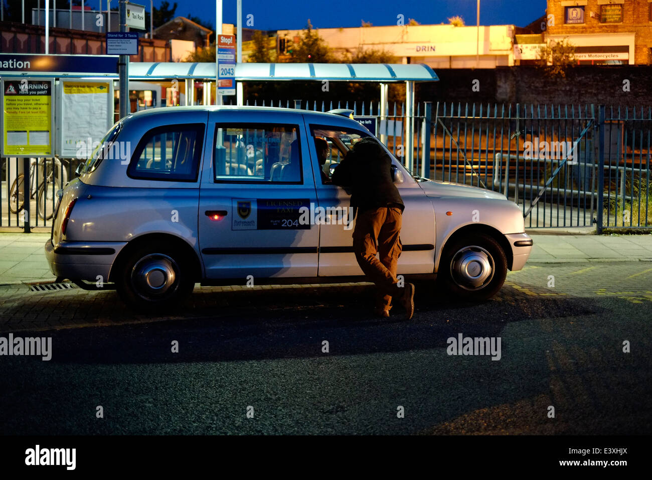 Uomo che parla di taxi cab driver a tarda notte England Regno Unito Foto Stock