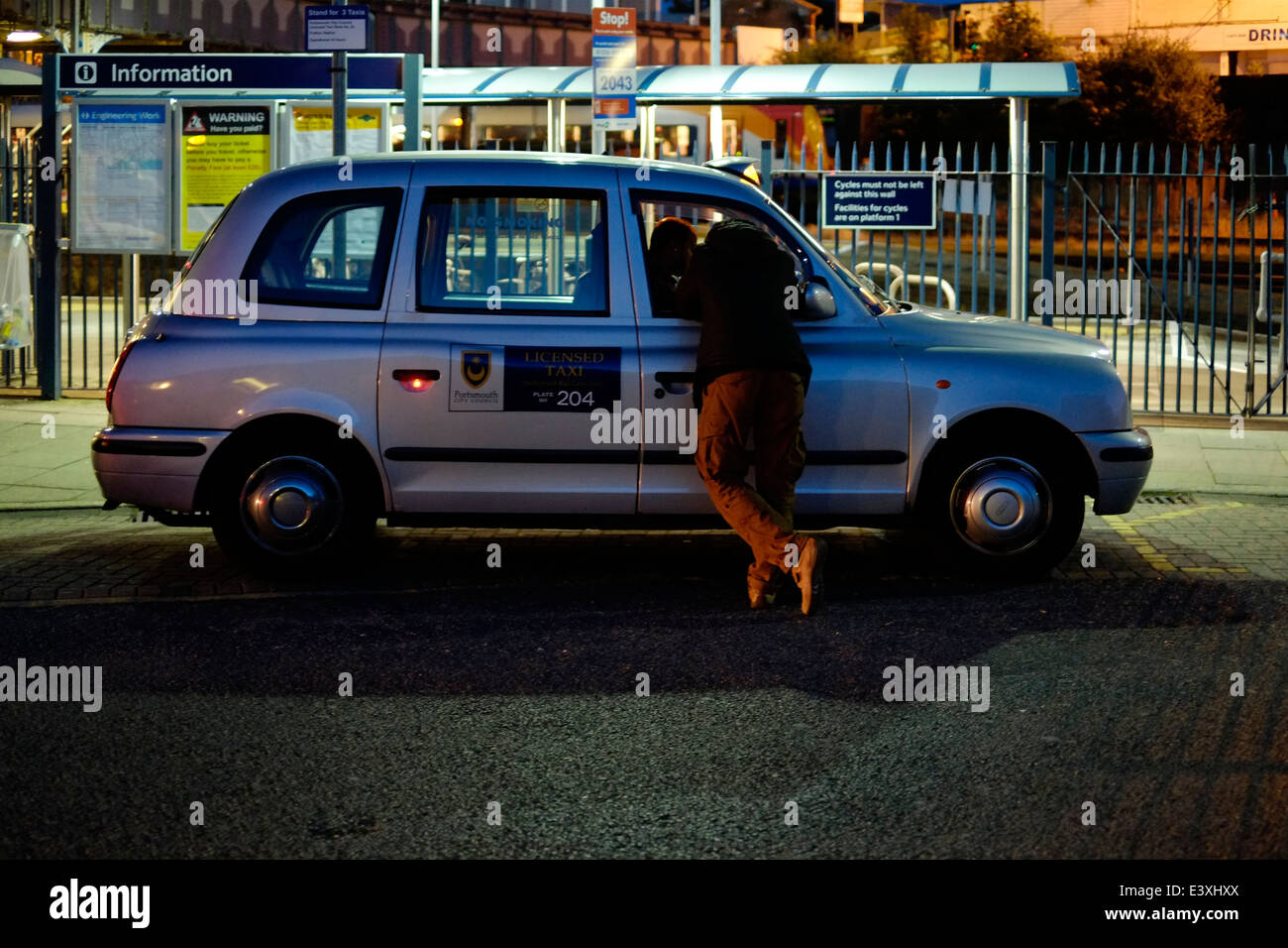 Uomo che parla di taxi cab driver a tarda notte England Regno Unito Foto Stock