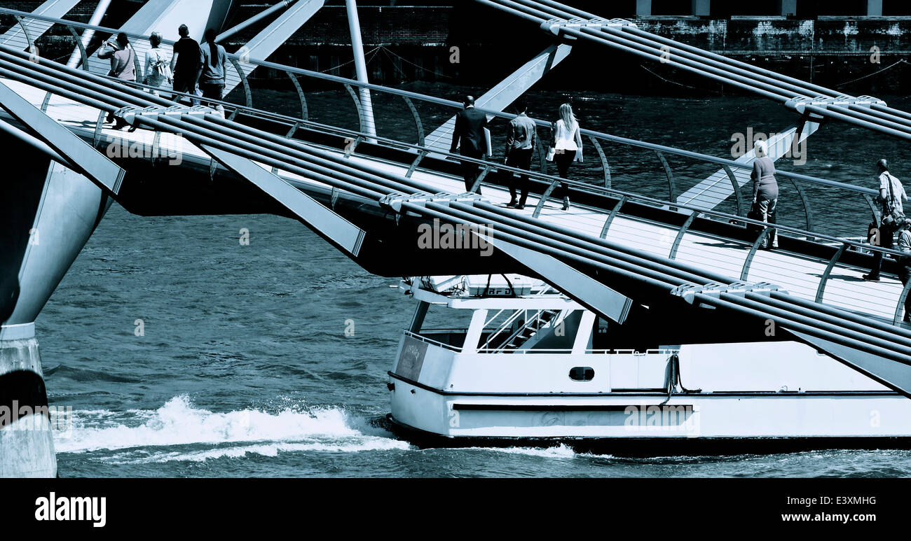 Turisti e pendolari sul Millennium Bridge come velocità del battello passato viaggiando verso est lungo il fiume Tamigi Londra Inghilterra Foto Stock