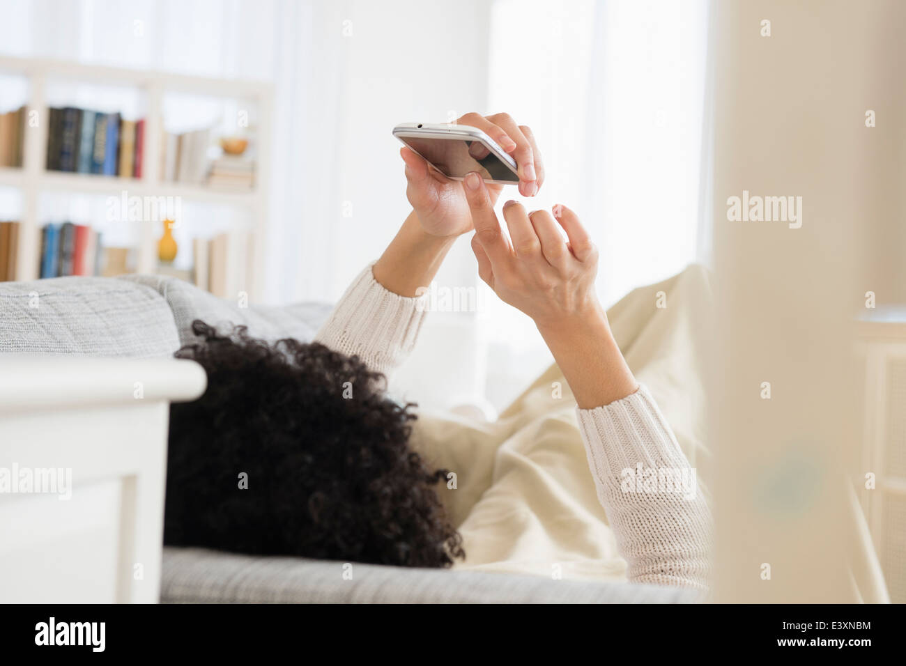 Nero donna tramite telefono cellulare sul divano Foto Stock