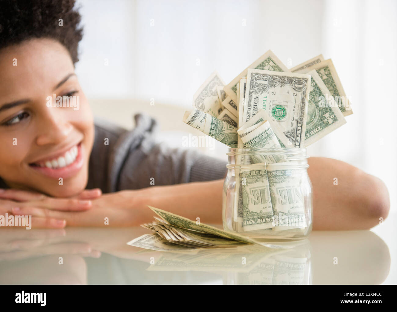 Nero donna ammirando un risparmio di denaro in vaso Foto Stock