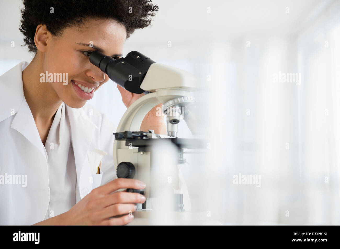 Scienziato nero usando microscopio in laboratorio Foto Stock