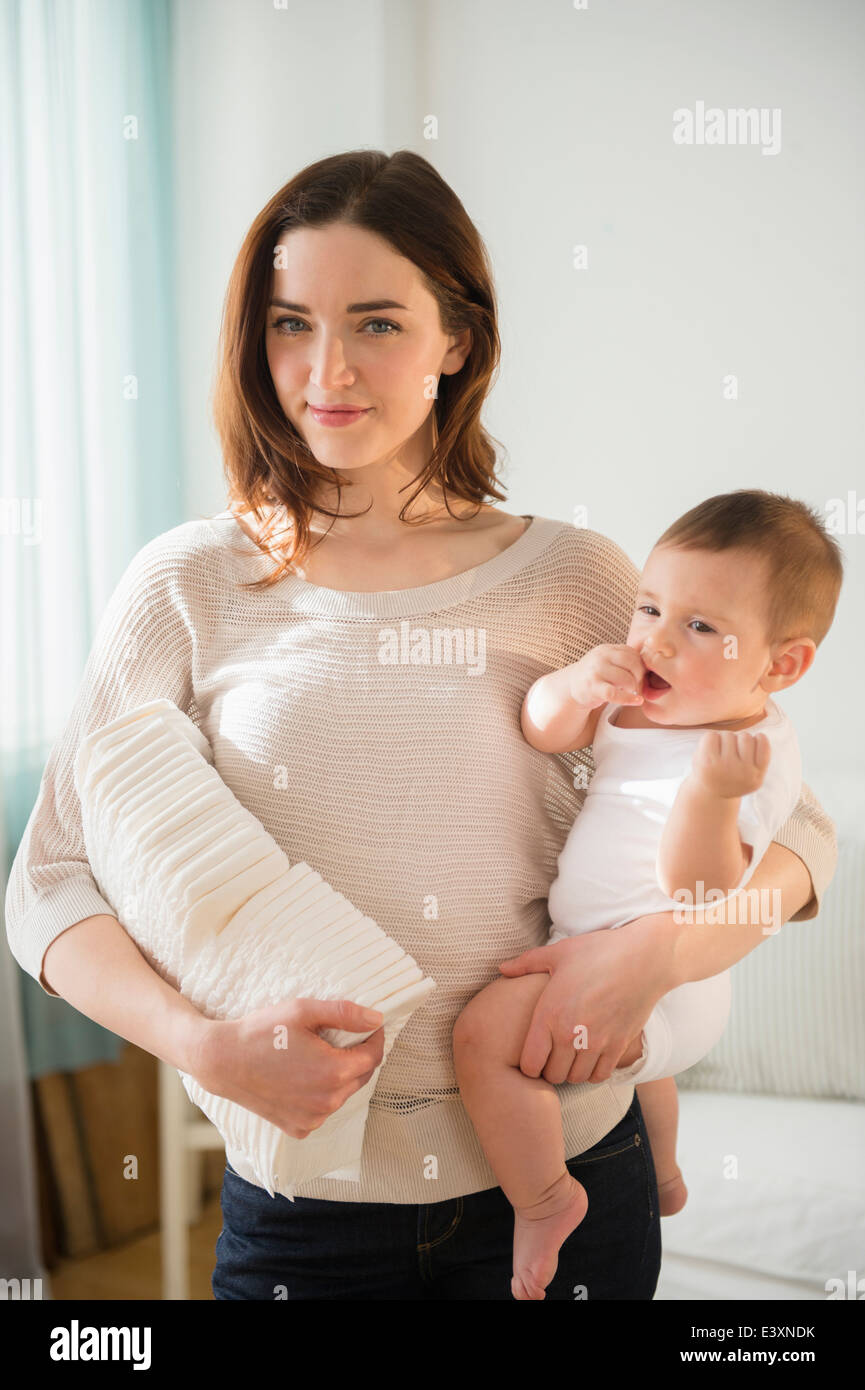 La madre del bambino di contenimento e la pila di pannolini Foto Stock