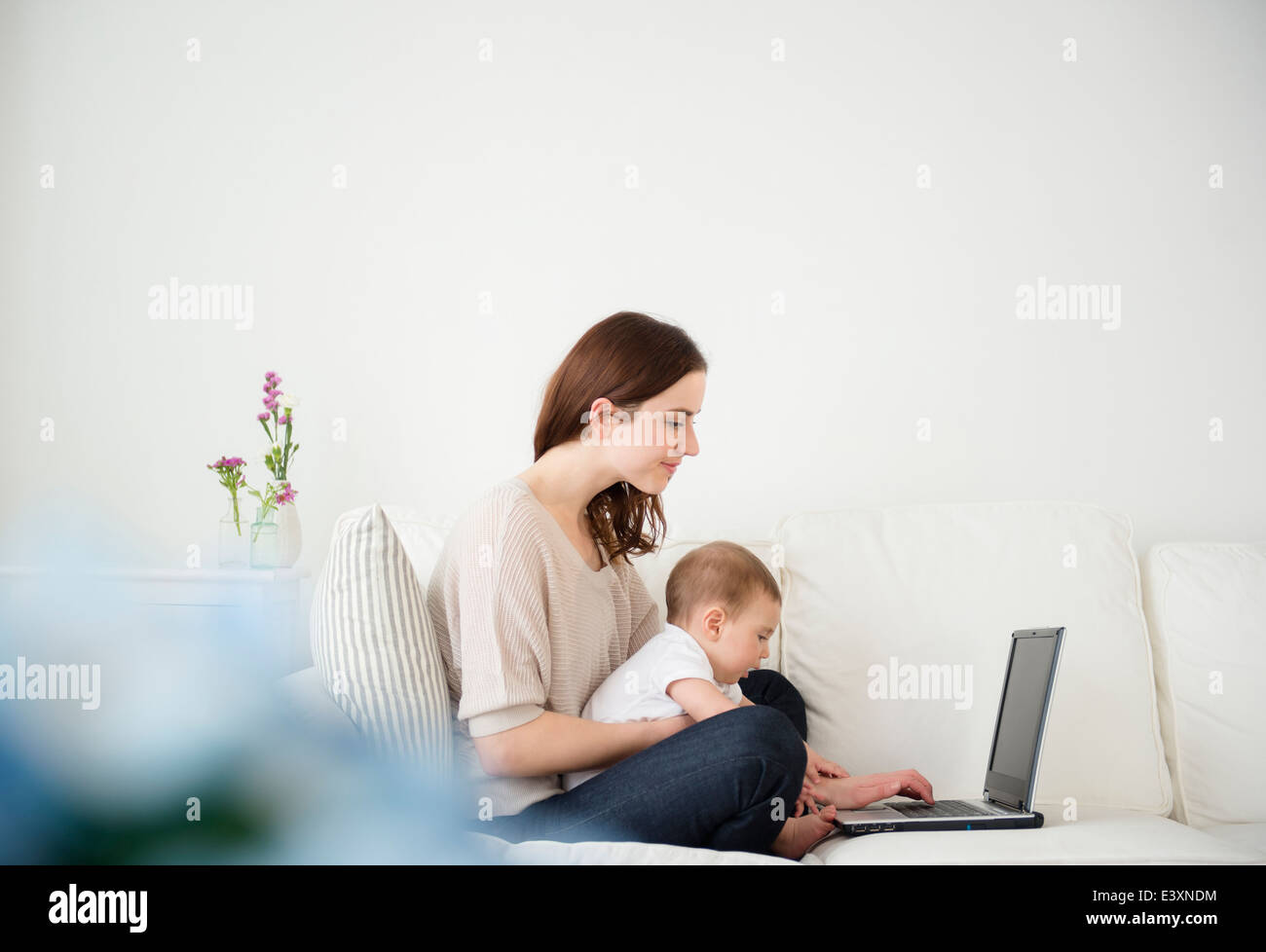 La madre e il bambino tramite computer portatile sul divano Foto Stock