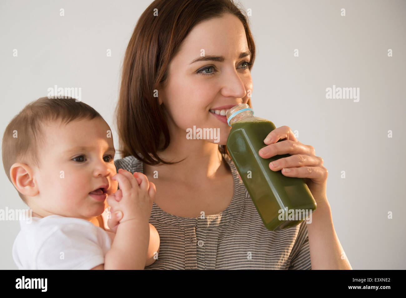 Azienda madre e bambino bere il succo verde Foto Stock