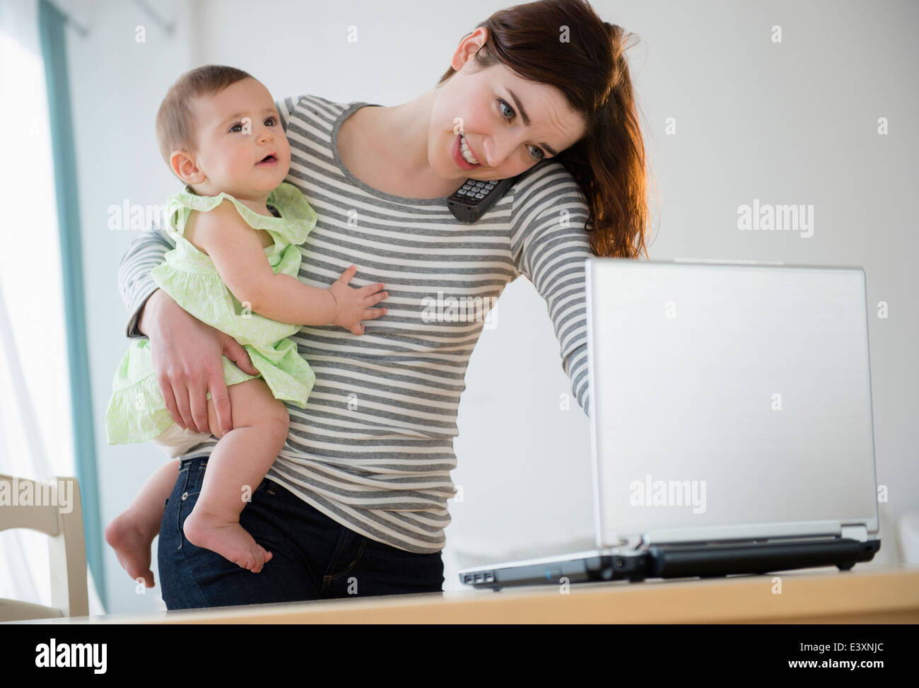 Il multitasking madre con bambino Foto Stock