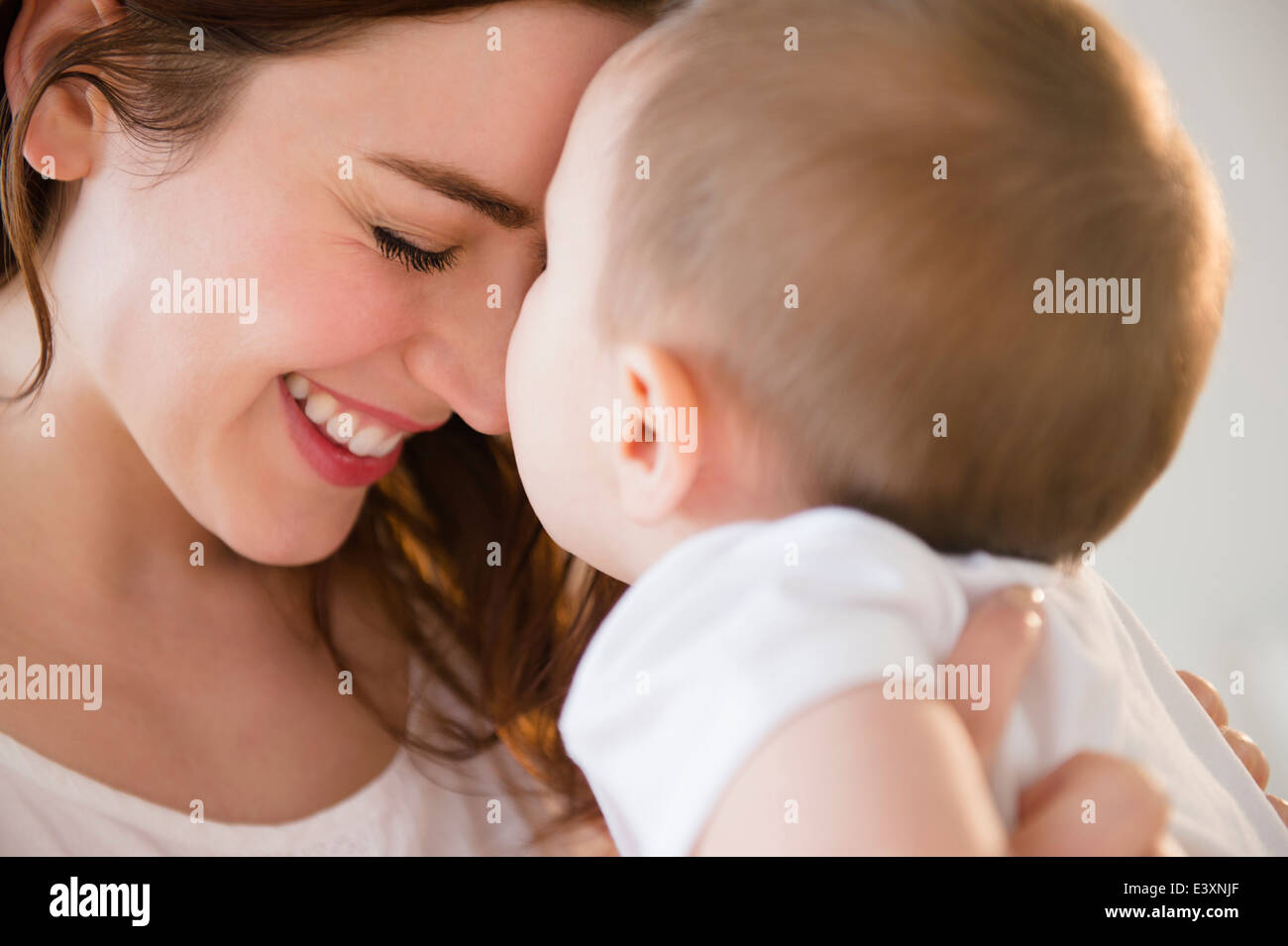 Madre sorridente cullano baby Foto Stock