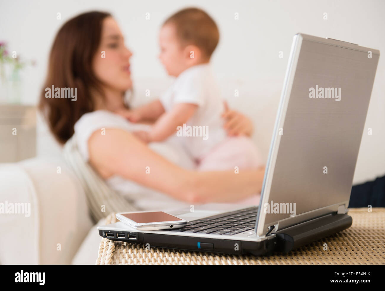 Computer portatile e un telefono cellulare accanto a madre con bambino Foto Stock