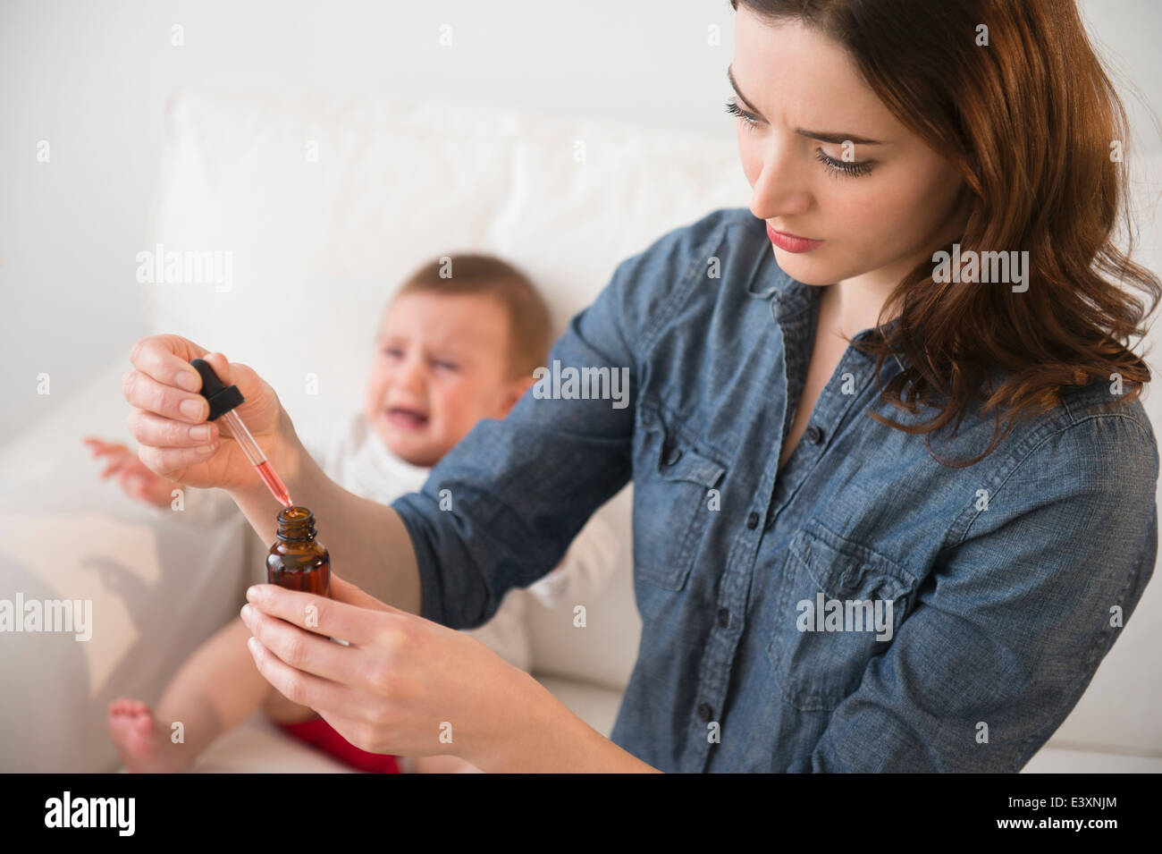 Madre dando Gridando bambino medicina Foto Stock