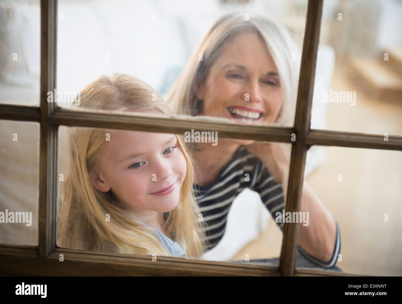 Senior donna caucasica e nipote a guardare fuori dalla finestra Foto Stock