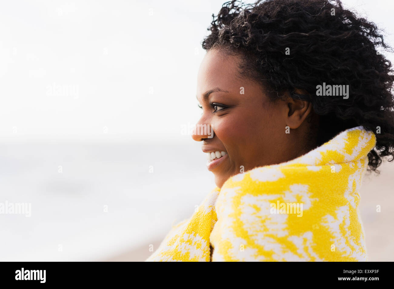 African American donna avvolta in asciugamano sulla spiaggia Foto Stock