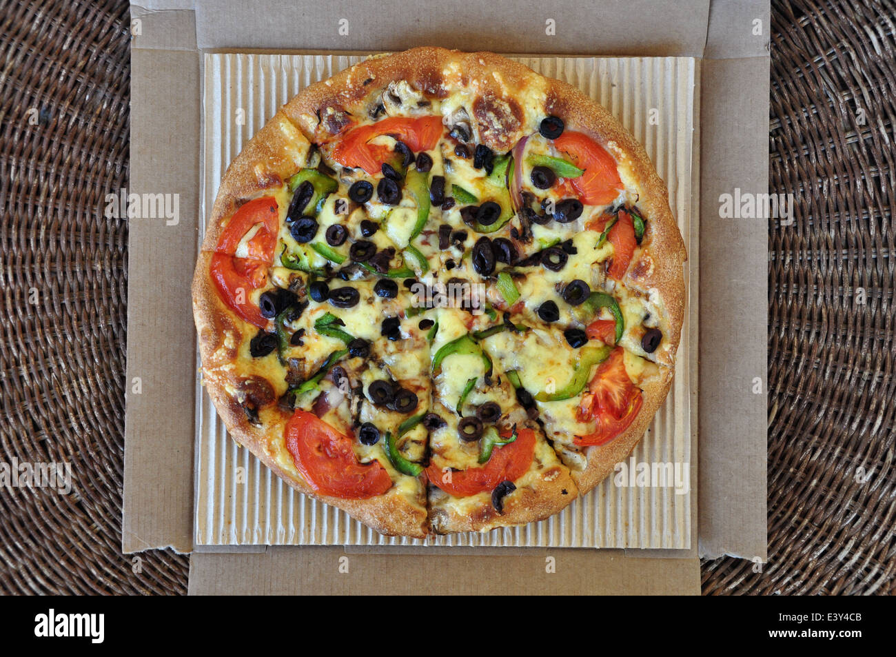 Pizza vegetariana con pomodoro, olive, pepe, i funghi e le cipolle confezionate in scatola di cartone. Italiano il cibo da asporto sfondo. Foto Stock
