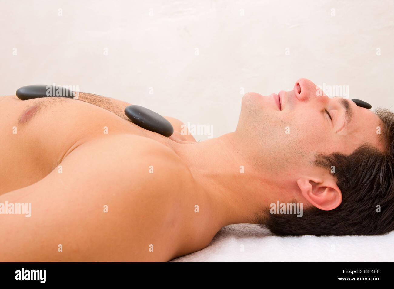 Giovane uomo godendo di un massaggio con pietre calde Foto Stock