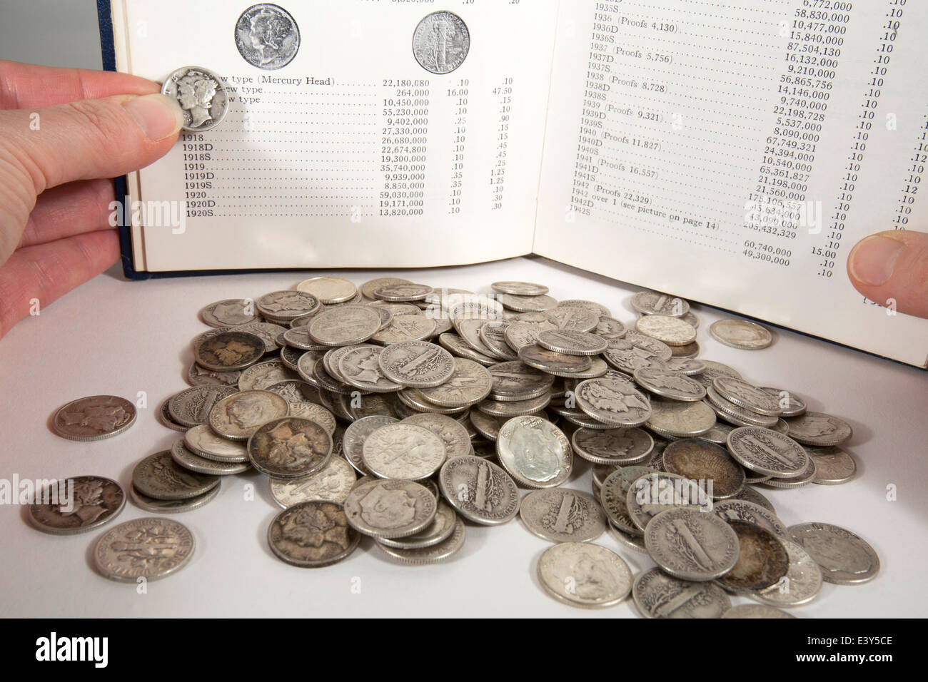 Pila di spiccioli di argento con una donna tenendo un mercury dime contro una foto in una raccolta di monete preziose guida rari Foto Stock