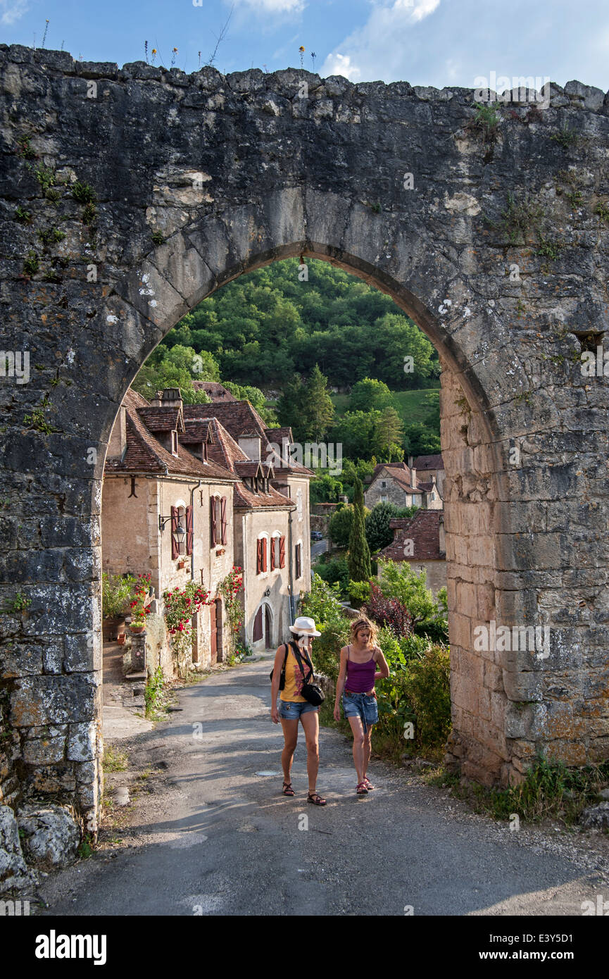 I turisti a piedi attraverso town gate presso il villaggio medievale Saint-Cirq-Lapopie, Lot, Quercy, Midi-Pirenei, Francia Foto Stock