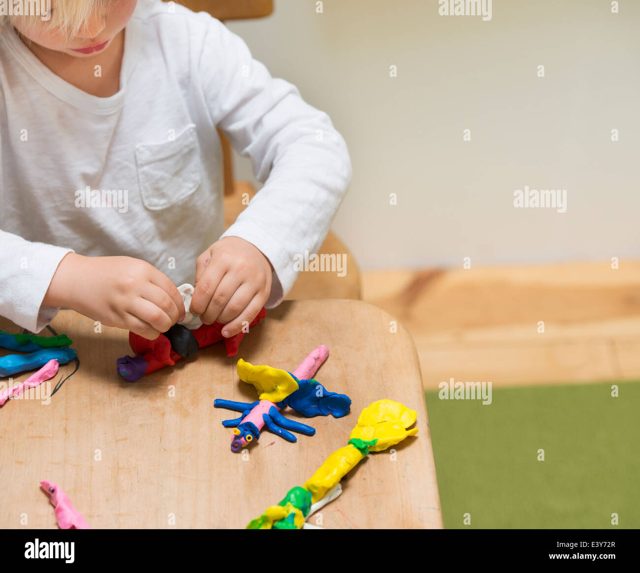 Ritagliato shot di tre anni di vecchio ragazzo giocando con la creta per modellare Foto Stock