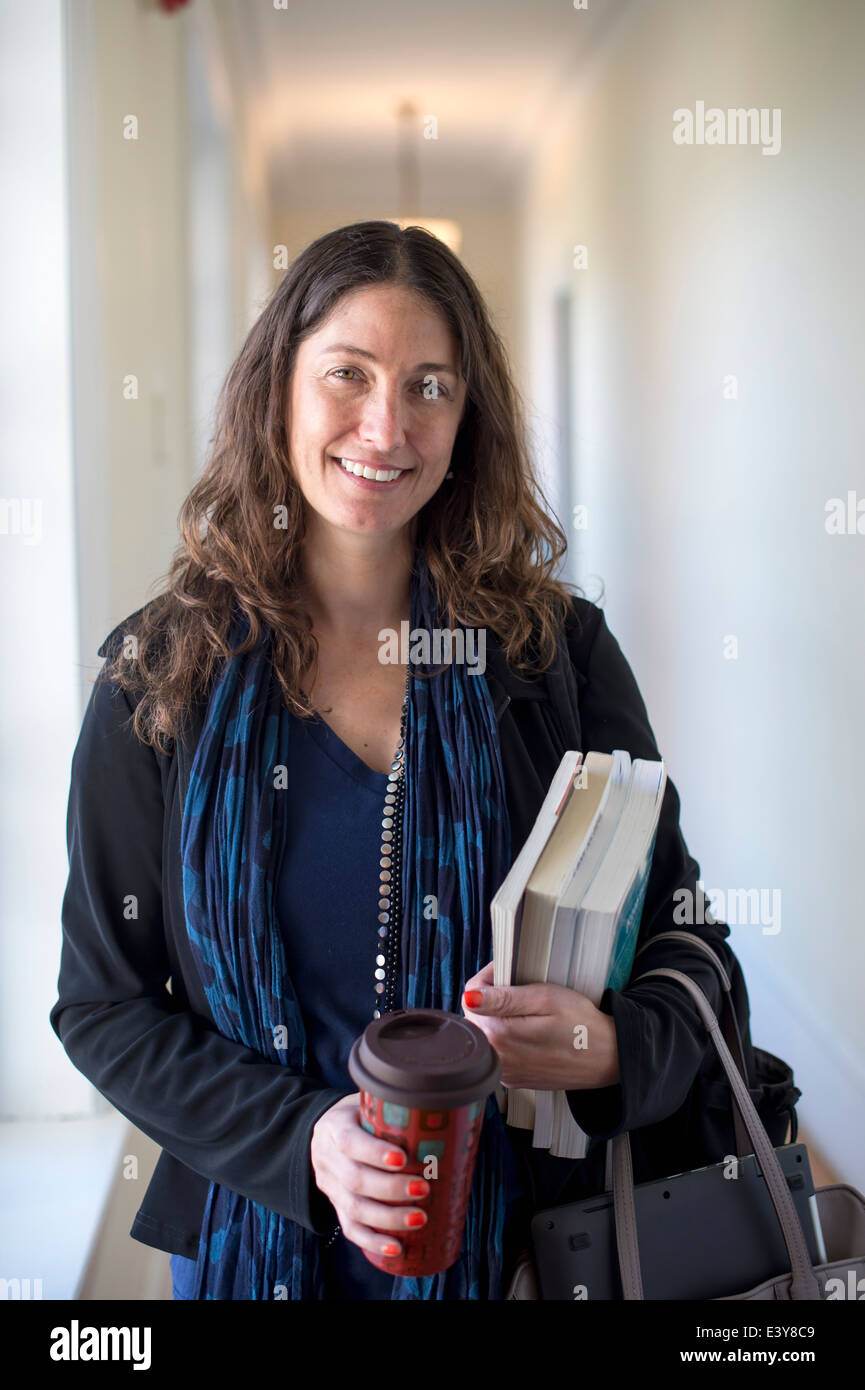 Docente in possesso di libri e caffè, ritratto Foto Stock