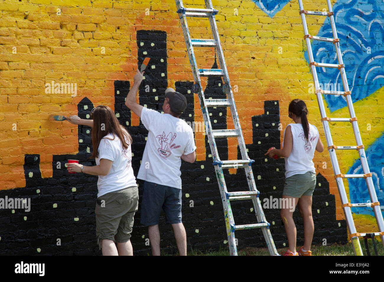 I volontari della vernice la parete di un edificio vacante a Detroit. Foto Stock