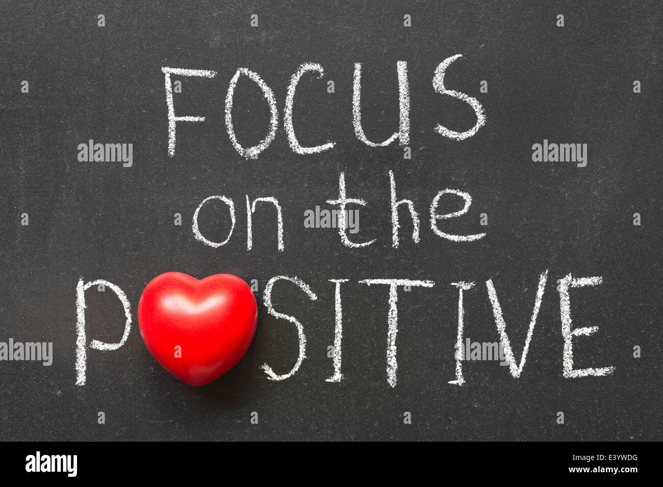 Focus sulla positiva una frase scritta a mano sulla lavagna con il simbolo del cuore di invece di o Foto Stock