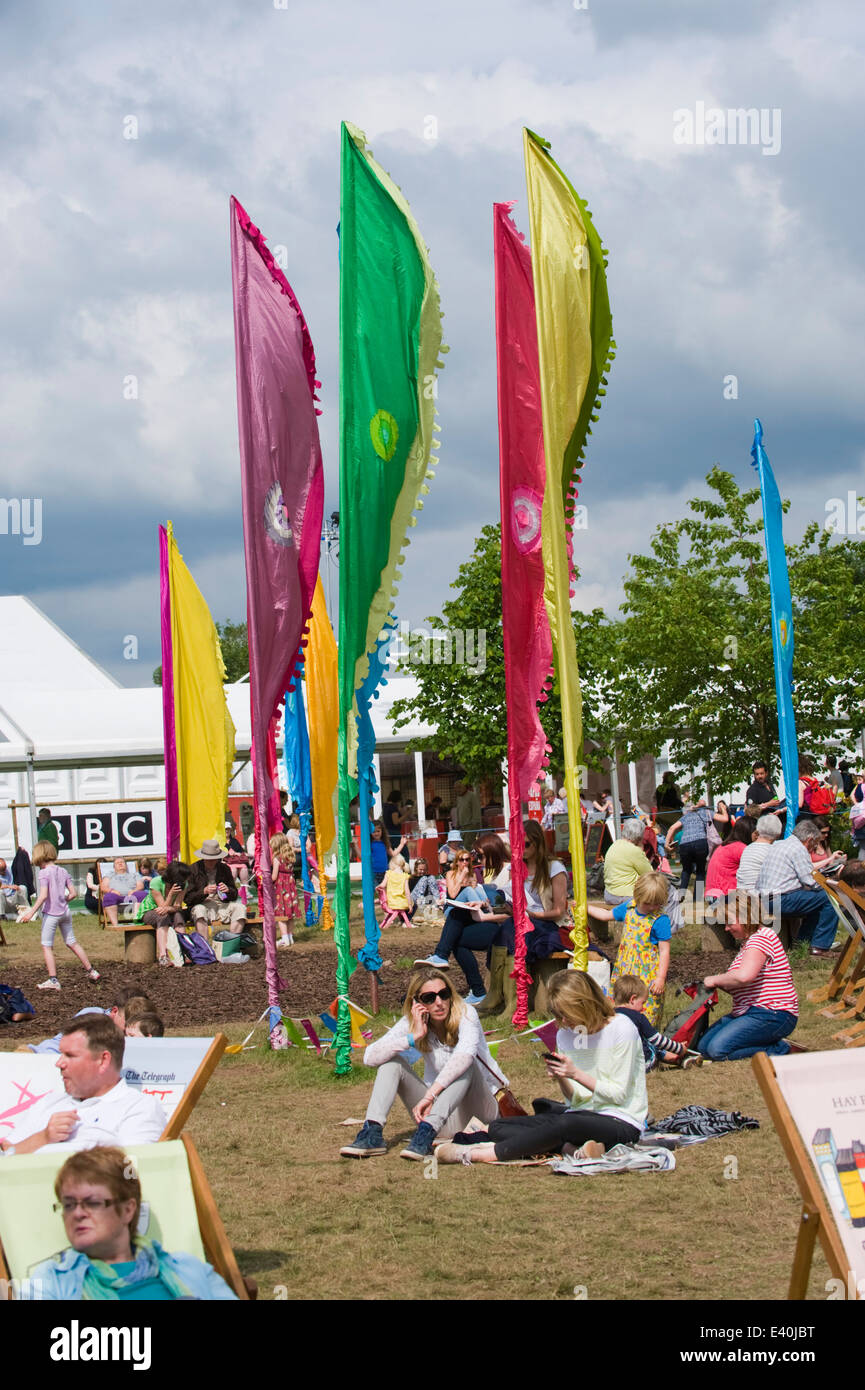 Visitatori tra le insegne colorate rilassarsi sul prato a Hay Festival 2014 ©Jeff Morgan Foto Stock