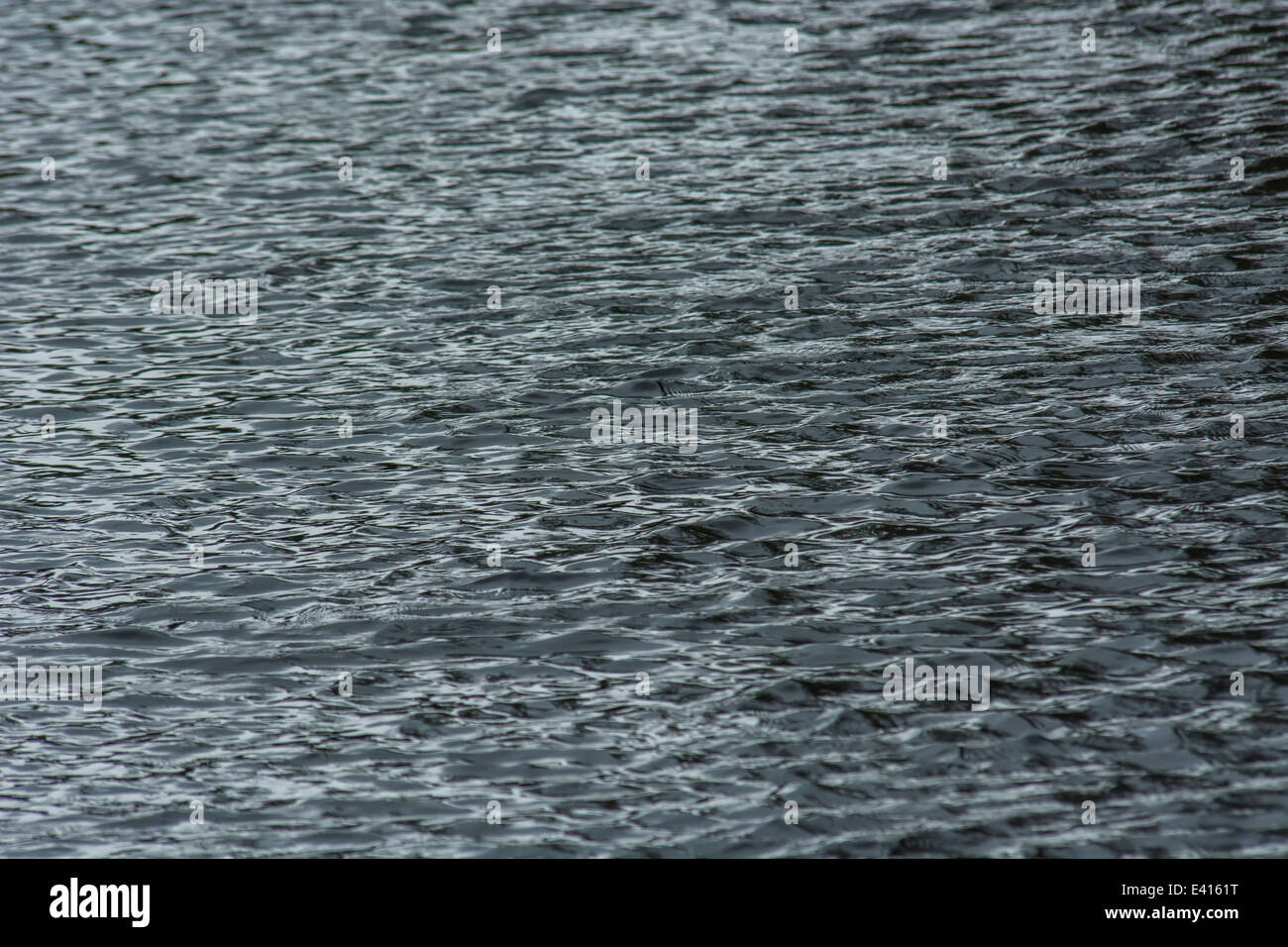 Riflessi di luce tempestosa nel fiume Fowey a Lostwithiel. Effetto ripple. Acqua come merce, mercato commerciale di acqua. Foto Stock