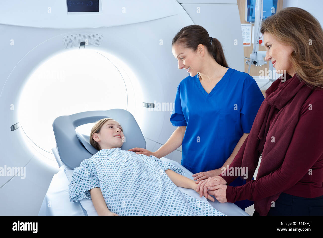 Radiologo e madre rassicurante ragazza di andare in CT scanner Foto Stock