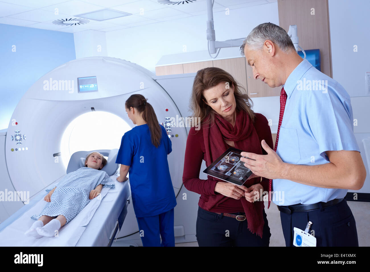 Medico e madre guardando a scansione, ragazza di andare in CT scanner Foto Stock