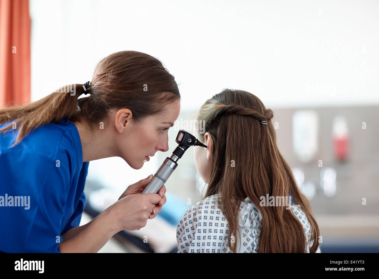 L'infermiera utilizzando otoscopio sulla ragazza Foto Stock