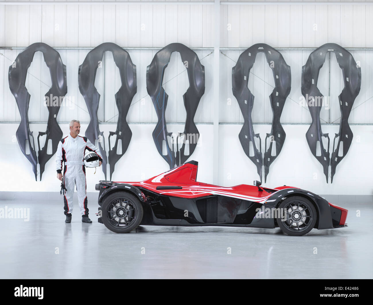 Racing driver con supercar in fabbrica con fibra di carbonio auto gusci del corpo appeso alla parete Foto Stock