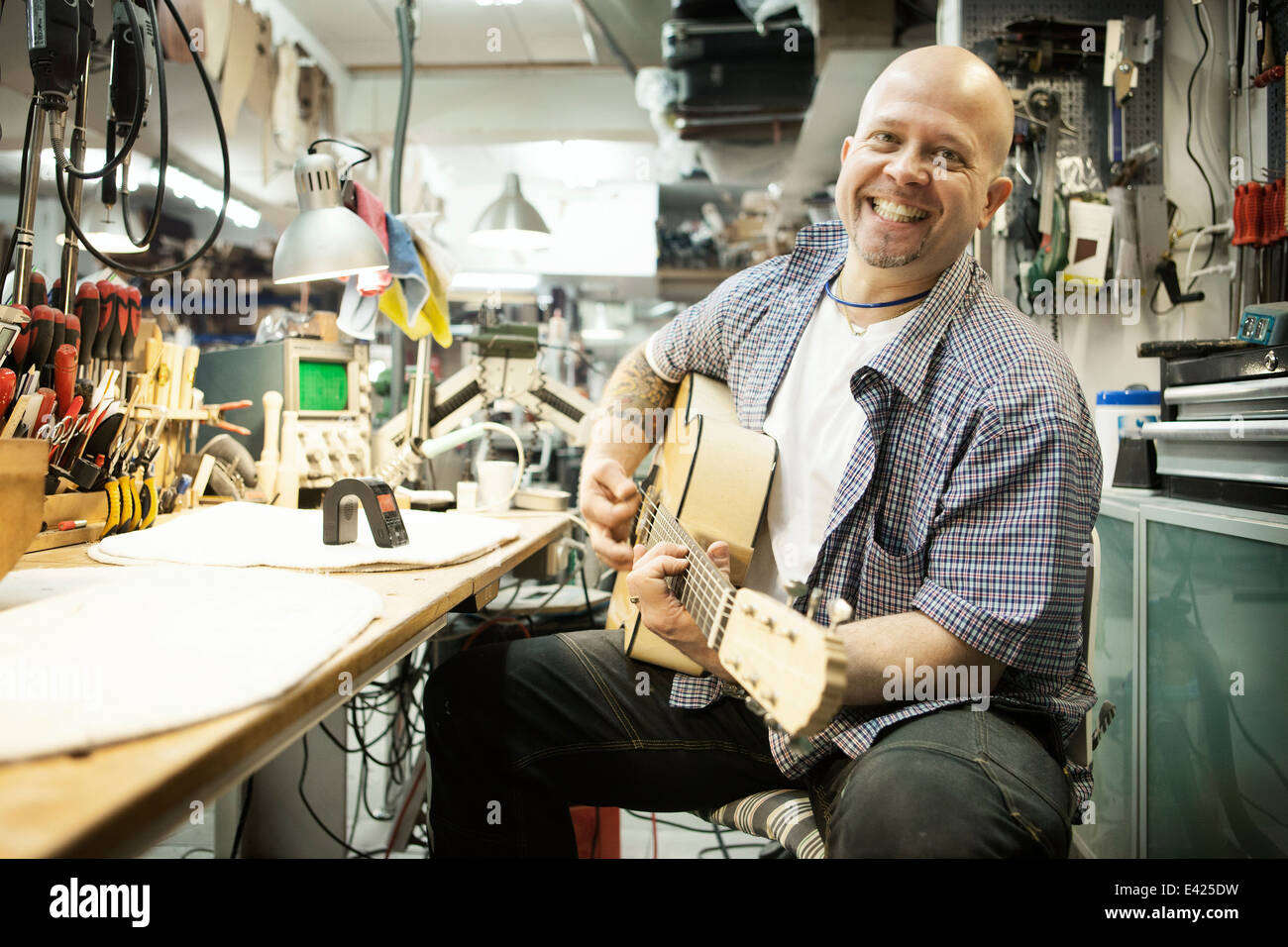 Ritratto di liutaio tuning chitarra acustica in officina Foto Stock