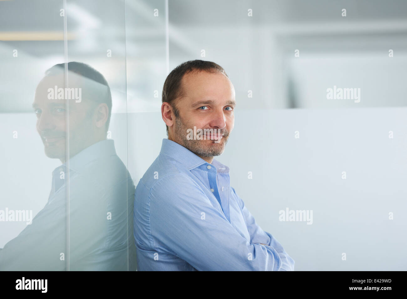 Imprenditore appoggiata contro la parete riflettente Foto Stock