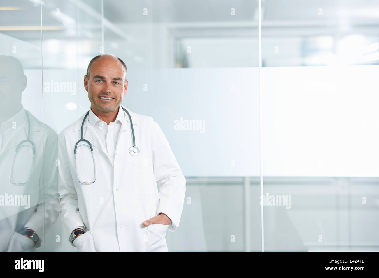 Medico maschio appoggiata contro la parete riflettente Foto Stock