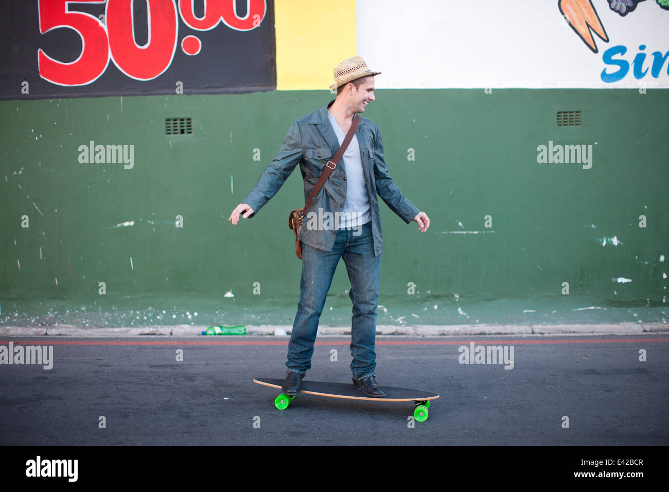 Metà maschio adulto lo skateboard su una strada di città Foto Stock