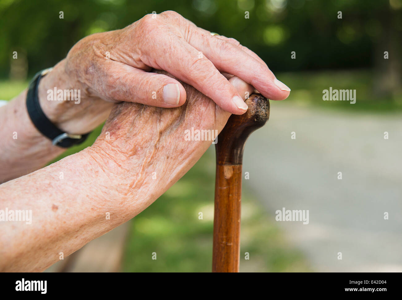 Senior donna con le mani in mano, tenendo bastone da passeggio Foto Stock