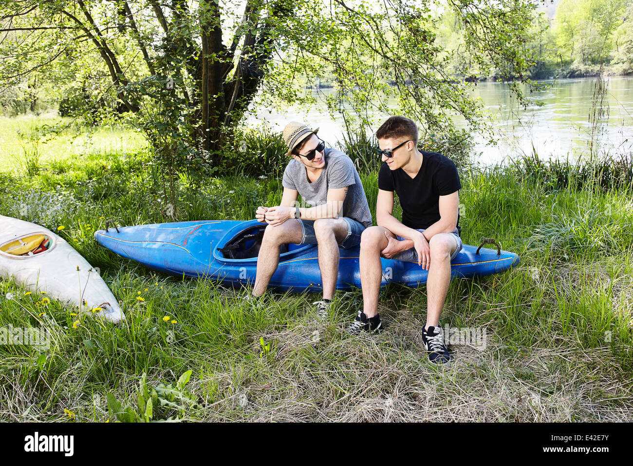 Due giovani uomini seduti su una canoa Foto Stock