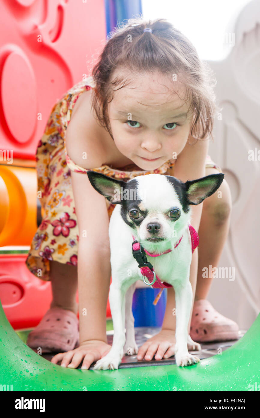 Giovane ragazza e il suo cane giocando su una slitta presso il parco giochi Foto Stock