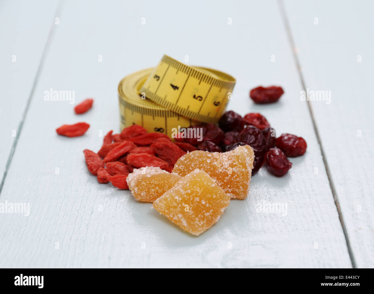 Bacche di Goji, cranberry, zenzero candito e nastro di misurazione, il concetto di salute Foto Stock