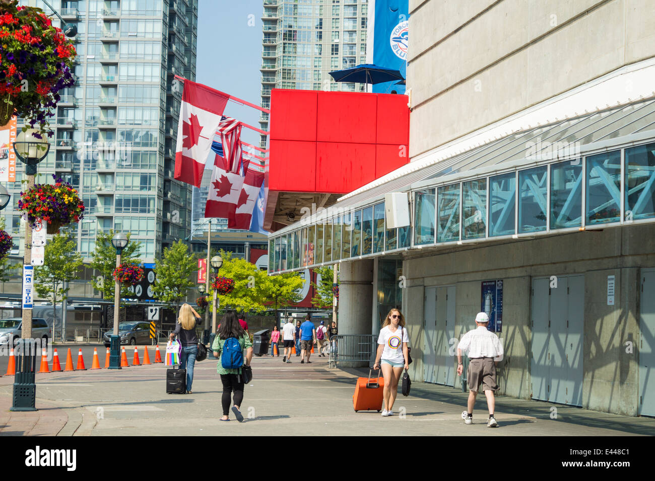 La gente a piedi nella parte anteriore del Rogers Centre nel centro cittadino di Toronto con la bandiera canadese a volare su un giorno di estate Foto Stock