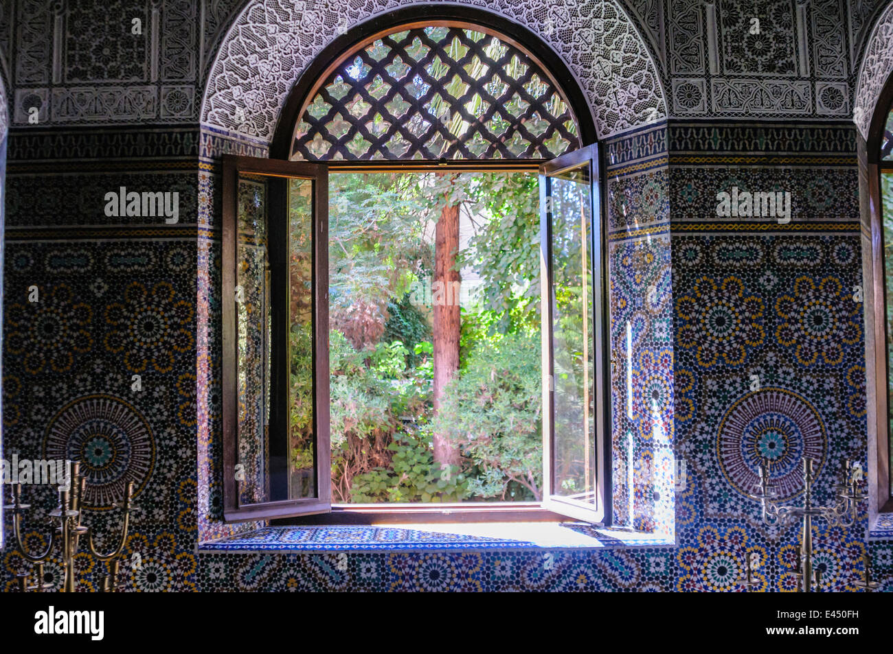 Ornati di piastrelle di ceramica sulla parete intorno a una finestra che guarda fuori in un giardino di una casa marocchina, Marrakech, Marocco Foto Stock