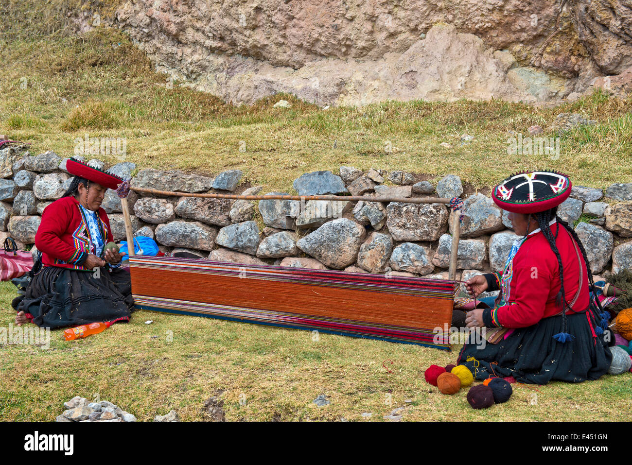 Due donne anziane indossare cappelli, gli Indiani Quechua in abito tradizionale, accovacciata sul pavimento lavorando sulla barella di un telaio di tessitura Foto Stock
